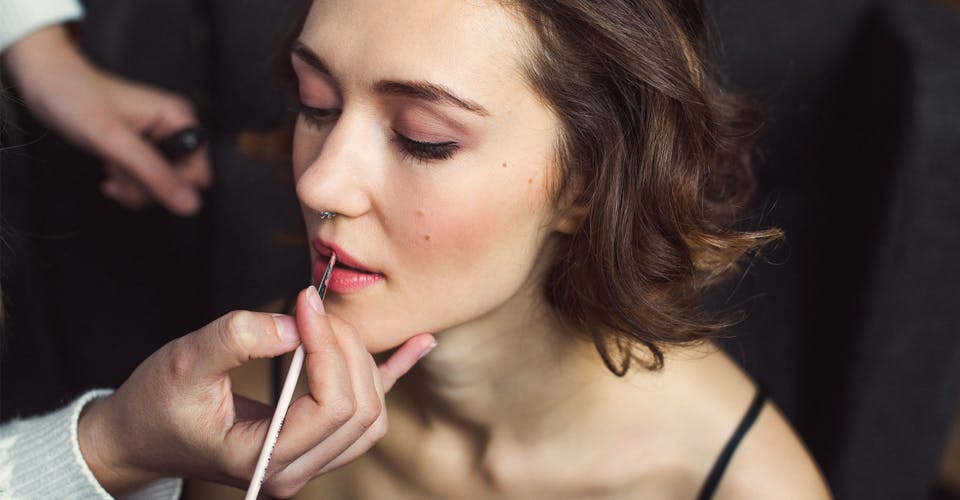 makeup artist applying liptstick on a client