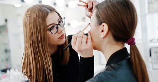 makeup artist applying liptstick on a client